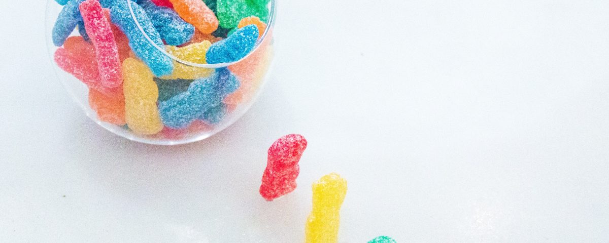 Three gummy bears marching into a bowl of gummies, symbolizing the fun and playful nature of THC edibles.