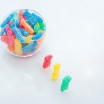 Three gummy bears marching into a bowl of gummies, symbolizing the fun and playful nature of THC edibles.