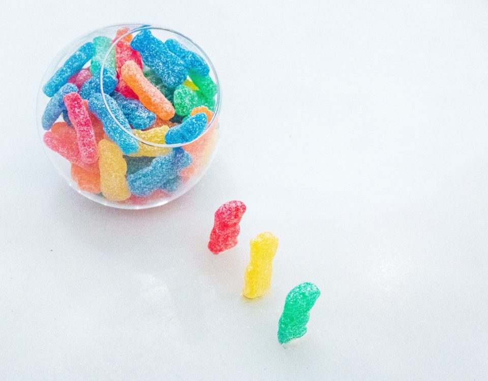 Three gummy bears marching into a bowl of gummies, symbolizing the fun and playful nature of THC edibles.